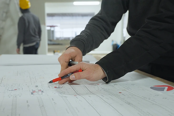 person drawing and pointing at blueprint plans